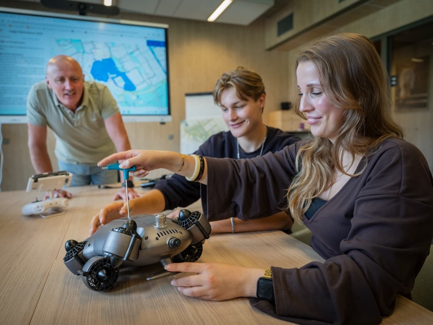 Docent en studenten werken samen aan een onderwaterdrone in het lokaal