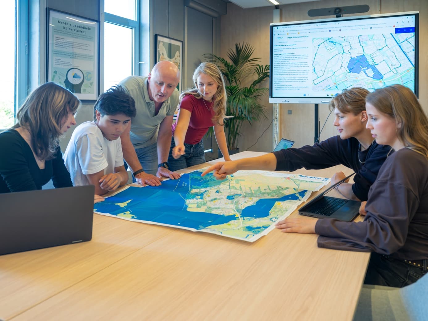 Studenten en docent bestuderen een waterkaart van het gebied