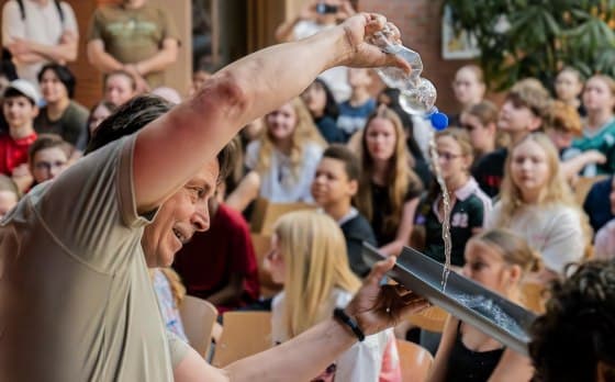 Waterexperiment met een fles en een bak voor een zaal vol leerlingen tijdens de School Take-Over