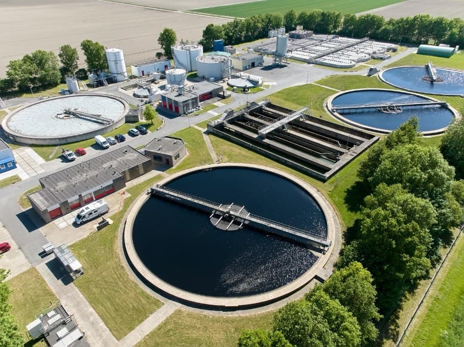 Luchtfoto van een rioolwaterzuivering met ronde nabezinktanks, beluchtingsbassins en bedrijfsgebouwen